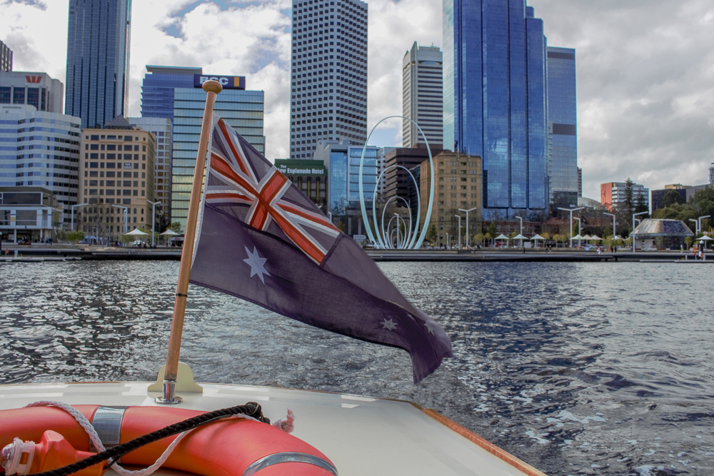 Australian flag flying from rear of Little Ferry Co, Perth city in background.